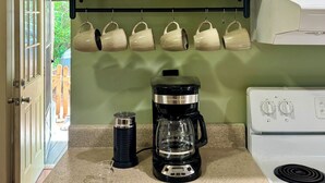 Eine Küche mit Kaffeemaschine, Wasserkocher und verschiedenen Küchenutensilien auf der Arbeitsfläche.