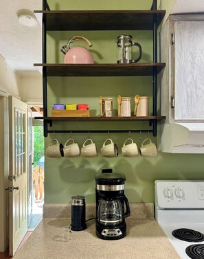 A kitchen with a coffee maker, a kettle, and various kitchen utensils on the counter. - Cozy, Well-Appointed Cottage By Blue Ridge Parkway (Asheville)