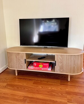 A wooden entertainment center with a flat-screen TV mounted above it. - Cozy, Well-Appointed Cottage By Blue Ridge Parkway (Asheville)