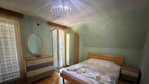 A bedroom with a wooden bed, a dresser, a mirror, and a window with blinds.