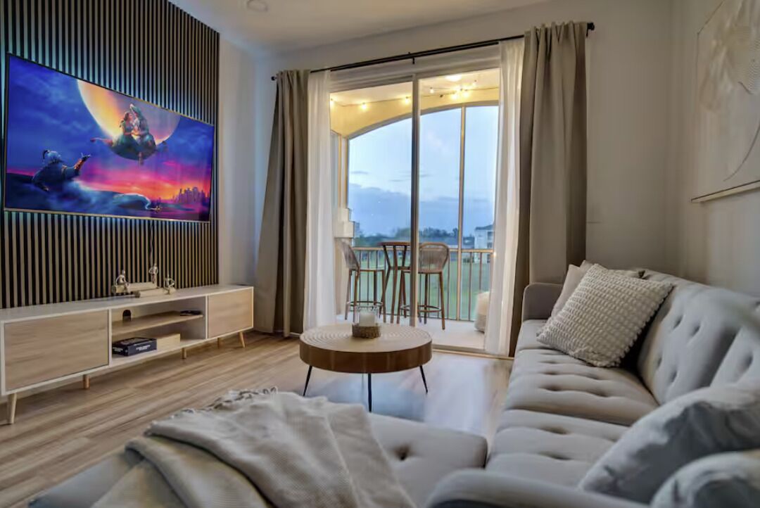 Un salon moderne doté d’un téléviseur à écran plat, d’un canapé, d’une table basse et d’un balcon offrant une vue agréable.