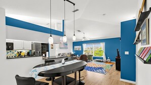 A modern kitchen with a dining area, a ceiling fan, and a view of the outdoors.