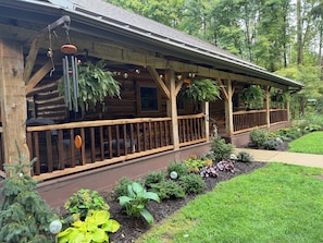 A rustic log cabin with a porch, surrounded by a well-maintained garden.