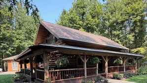 Eine Holzhütte mit Veranda, umgeben von einem gepflegten Rasen und Bäumen.