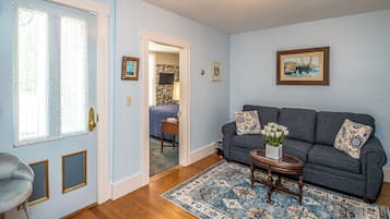 A living room with a blue sofa, a small table with a vase, and a patterned rug.