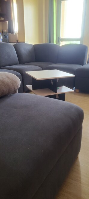 Een woonkamer met een donkerbank, een kleine tafel en een waterdispenser op de achtergrond.