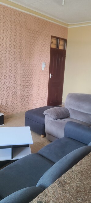A living room with a sofa, a table, and a patterned wall. - Adorable 1-bedroom building in Kwale County perfect for relaxing stay (Kwale County)