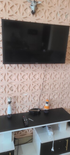 A flat-screen TV mounted on a wall with a decorative panel in the background. - Adorable 1-bedroom building in Kwale County perfect for relaxing stay (Kwale County)