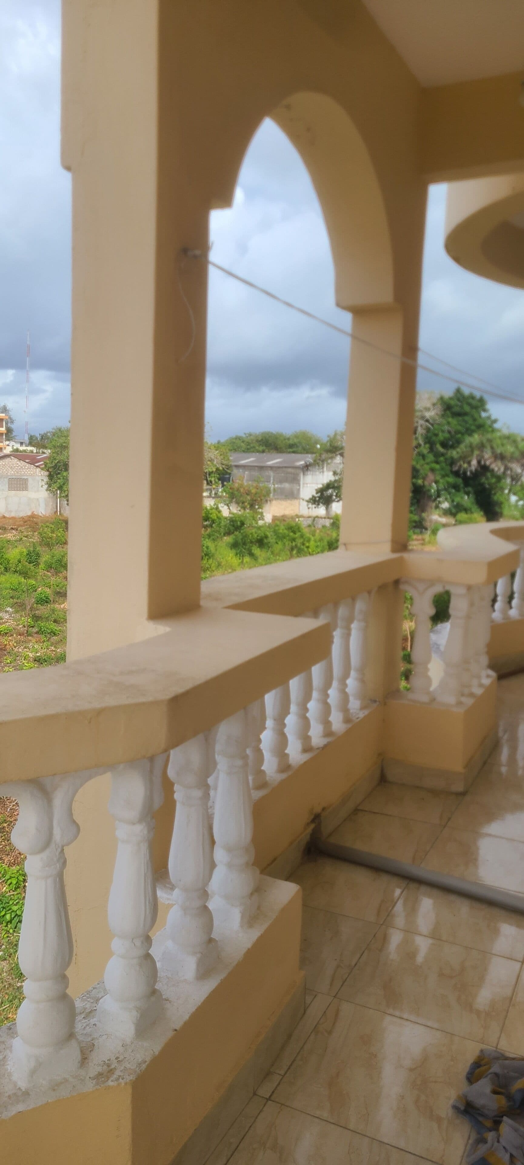 A balcony with a beige railing and a view of a residential area.