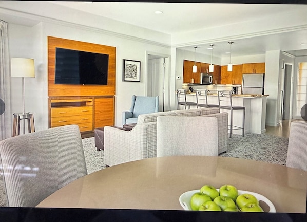 A modern living room with a dining table, a sofa, and a kitchen area with a bar.