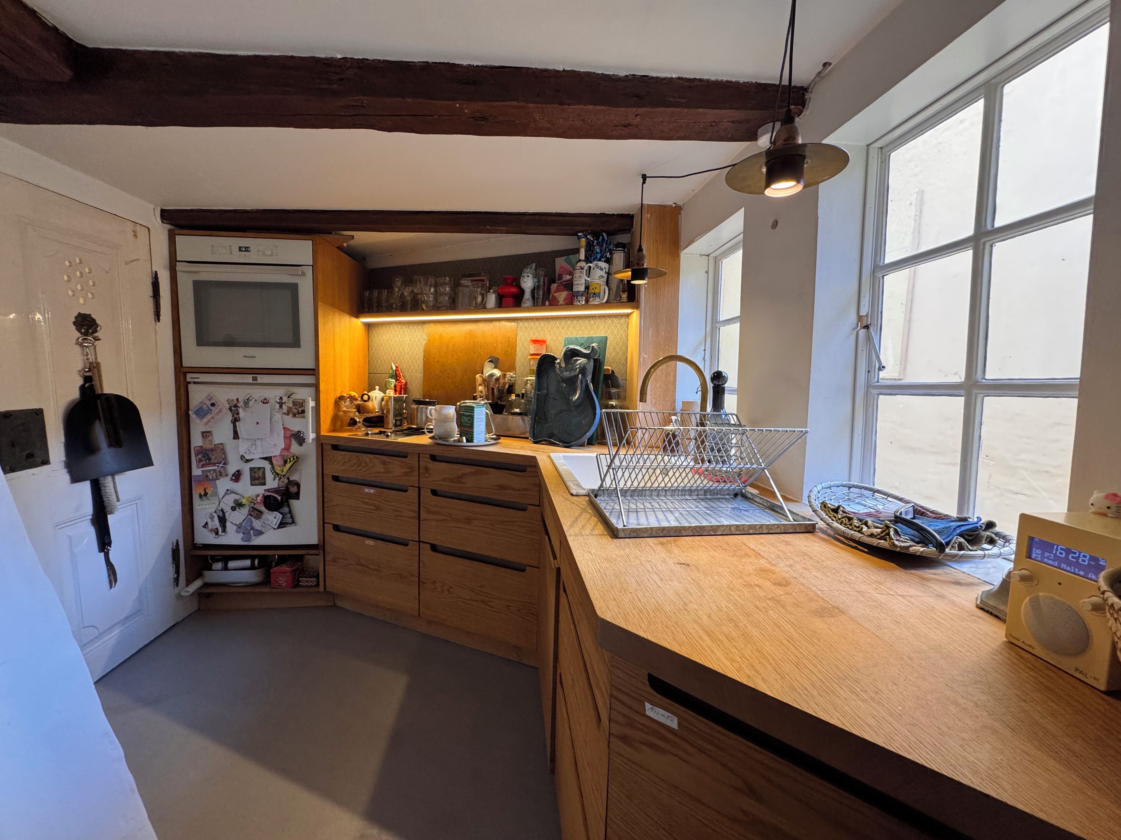 A kitchen with wooden cabinets, a refrigerator, a sink, and a window.