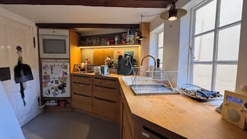 A kitchen with wooden cabinets, a refrigerator, a sink, and a window.