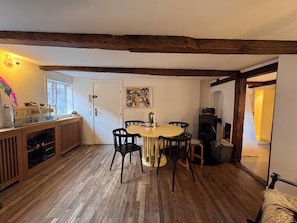 Une cuisine chaleureuse avec des poutres en bois, une table à manger avec des chaises, un poêle et une fenêtre donnant sur un beau paysage.