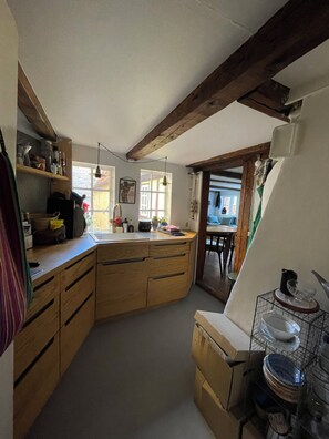 A kitchen with wooden cabinets, a sink, and a dining area visible through an open door. - Charming and historic apartment in the city center! (København)
