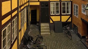 A narrow alleyway with a building featuring a half-timbered facade, a door, and a bicycle parked outside.