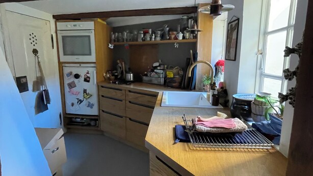 A compact kitchen with built-in appliances, wooden cabinets, and a window providing natural light.