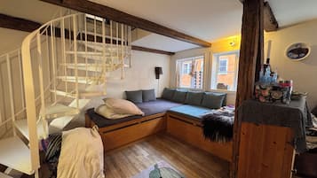 Una stanza con una scala a chiocciola, un divano letto, pavimento in legno e una finestra vista esterna.