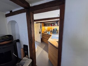 A narrow hallway with a wooden-framed archway leading to a kitchen area with wooden cabinets and a countertop.