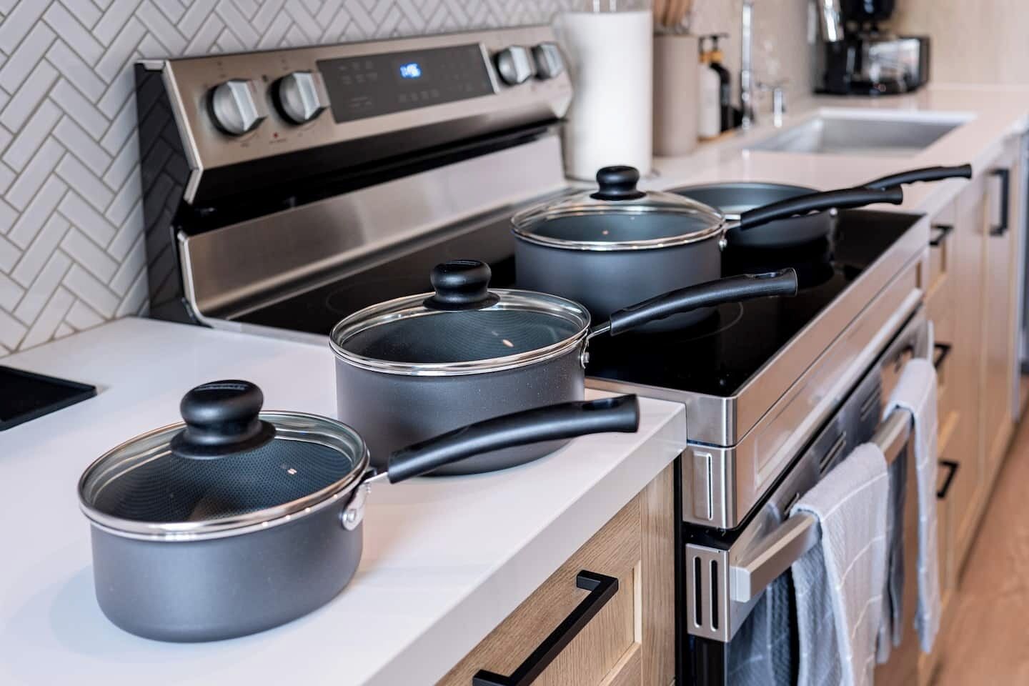 A modern kitchen with stainless steel appliances, including a stove and oven, and three pots on the counter.