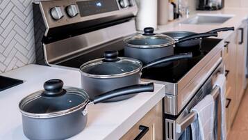 A modern kitchen with stainless steel appliances, including a stove and oven, and three pots on the counter.