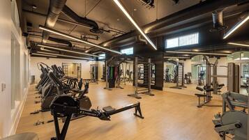 Un gimnasio con cintas de correr, máquinas de pesas y un espejo grande.