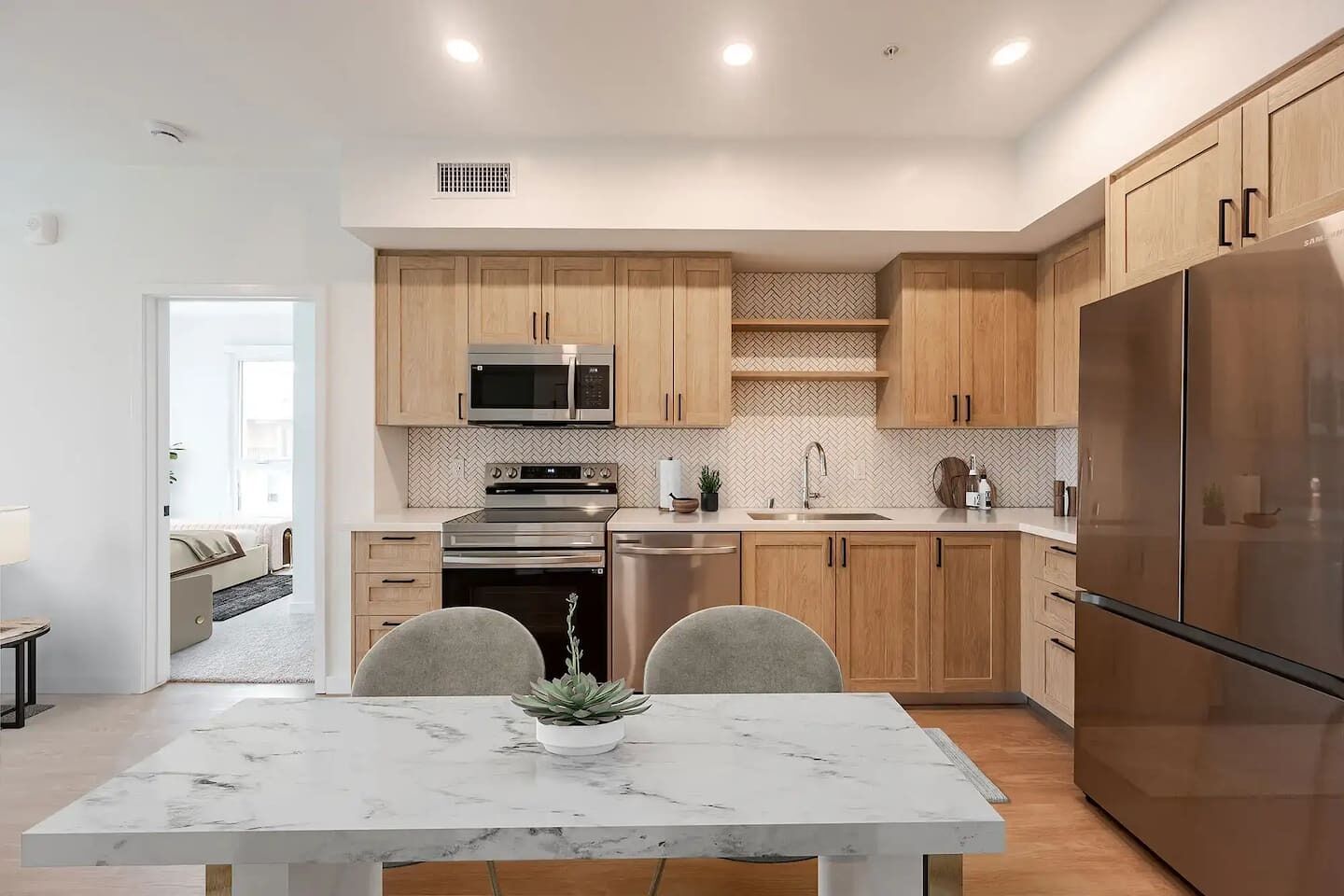 A modern kitchen with wooden cabinets, stainless steel appliances, and a marble countertop.