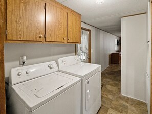 A laundry area with a washer and dryer, wooden cabinets, and a tiled floor. - 2-bedroom mobile home with a sleeping sofa in peaceful Mammoth Cave with AC. (Mammoth Cave)