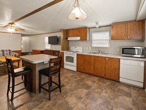 A compact kitchen with a central island, wooden cabinets, a microwave, and a stove. - 2-bedroom mobile home with a sleeping sofa in peaceful Mammoth Cave with AC. (Mammoth Cave)