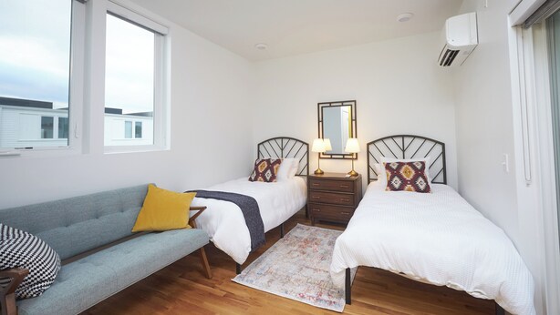 A bedroom with two single beds, a sofa, a mirror, and a window. - New Townhouse in Historic District of Chattanooga (Chattanooga)