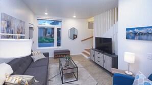 A modern living room with a sofa, coffee table, and a TV. - New Townhouse in Historic District of Chattanooga (Chattanooga)