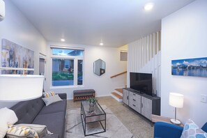 A modern living room with a sofa, coffee table, and a TV. - New Townhouse in Historic District of Chattanooga (Chattanooga)