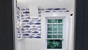 Un baño con inodoro, lavamanos y ventana con vistas al verdor.