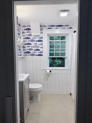 Ein Badezimmer mit Toilette, Waschbecken und einem Fenster mit Blick auf Grünflächen.