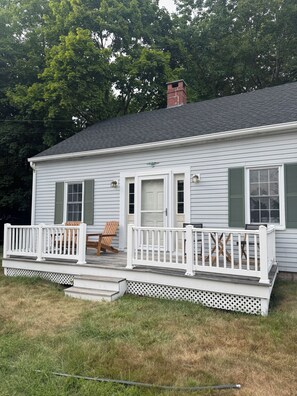 Une maison de plain-pied avec un porche à l’avant, une cheminée et une petite terrasse.