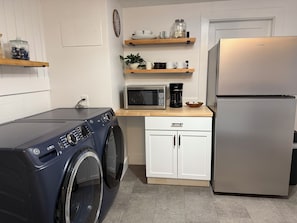 A compact kitchen with a washing machine, a microwave, a coffee maker, and a refrigerator. - Harbor View House - Southwest Harbor (Southwest Harbor)