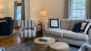 Una sala de estar con sofá, sillones, una mesa de centro y una alfombra estampada.