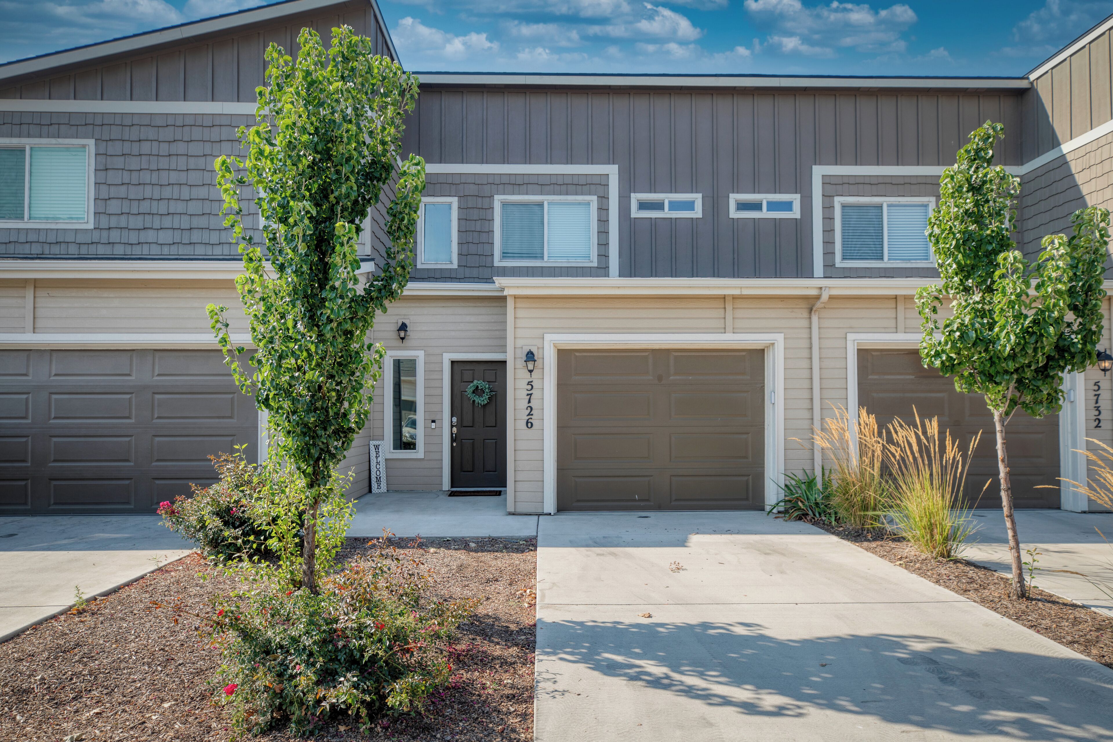 A two-story residential building with a garage on the ground floor and a front door with a wreath.