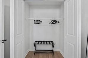 Ein begehbarer Kleiderschrank mit einer Bank und zwei Kleiderstangen.