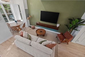 A modern living room with a sofa, chairs, a coffee table, and a flat-screen TV mounted on the wall. - Brand New 3BR Luxury DC Rowhome w/ Rooftop Patio• 5-10 mins from top attractions (Washington)