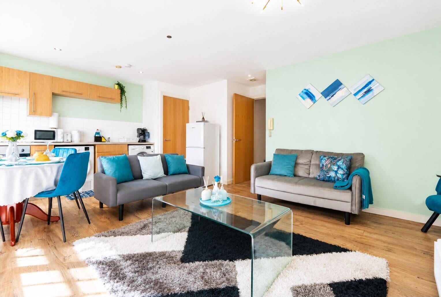 A modern living room with a sofa, a glass coffee table, and a dining area with a table and chairs.