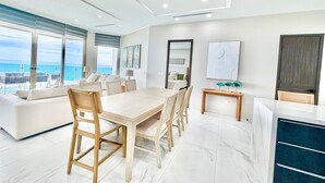Una moderna camera d'albergo con zona pranzo, un'ampia finestra vista mare e un letto con vista sulla città.