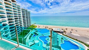 Un hotel con diversi piani, una grande piscina con varie sezioni e vista sulla spiaggia.