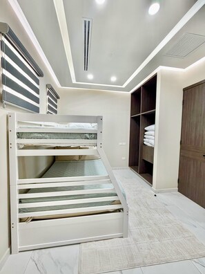 Ein Schlafzimmer mit Etagenbett, Einbauschrank und einer Decke mit Einbuchtung für Beleuchtung.