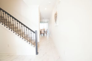A staircase with a handrail leading to a dining area with a table and chairs. - Newly Remodeled House Near Disney (Davenport)