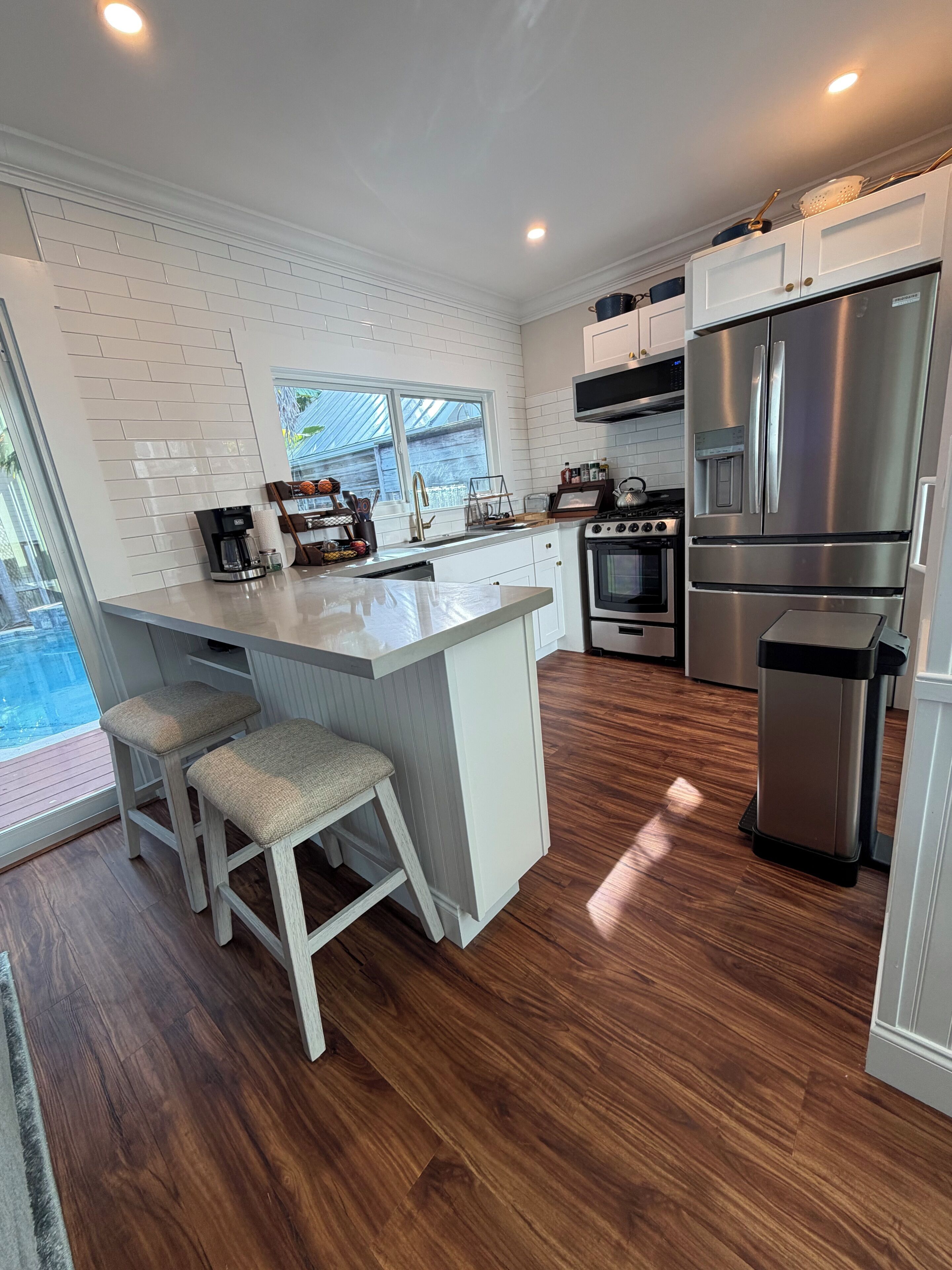 A modern kitchen with a central island, stainless steel appliances, and a view of the outdoors.