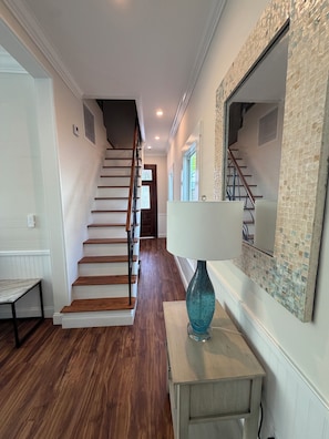 Eine Treppe, die zu einer zweiten Etage führt, ein Holztisch und eine Lampe auf einem kleinen Tisch.