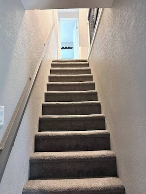 A carpeted staircase with a handrail leading to a door at the top. - The Windsor Exchange Retreat (Windsor)