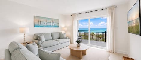A modern living room with a sofa, a coffee table, and a painting of sailboats.