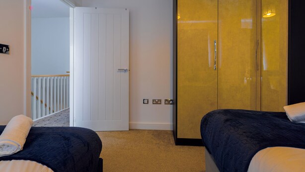 A hotel room with two beds, a wardrobe, and a door leading to a balcony. - E-Solace-  Etihad-Coop LIVE-Free Parking-Pool Table (Manchester)