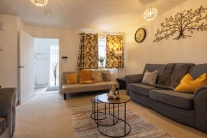 A living room with a sofa, a coffee table, and a patterned rug.